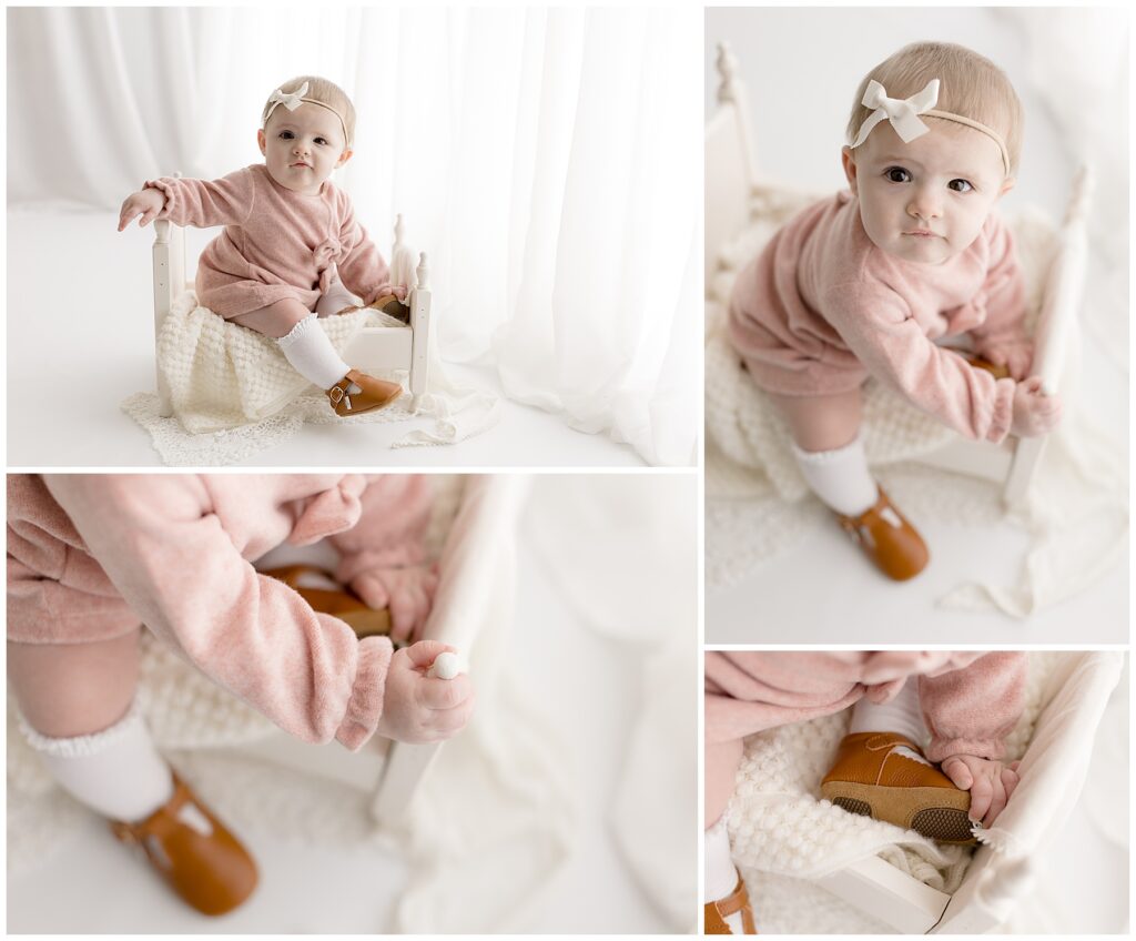Beautiful baby photography of a little one in her pink dress, headband, and knee socks with brown leather shoes in front of a wall of white sheer curtains and floor to ceiling windows.