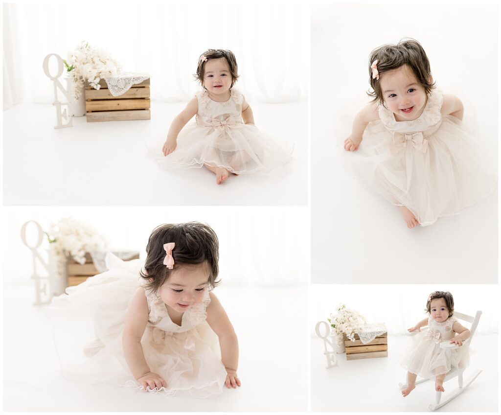 Smiley one year old girl with a gorgeous head of hair wears a beautiful cream-colored dress for her cake smash photography pictures