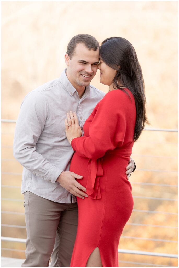 expectant couple laughs together while embracing
