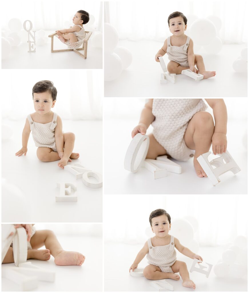baby boy poses for first birthday photos in white studio with letters that spell out ONE